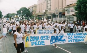 Participantes reunidos na Caminhada da Paz com faixa de Marcelino D'Almeida